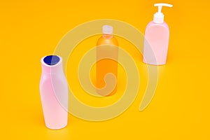 Conveniently shaped containers. Cosmetic bottles in row. Refillable bottles yellow background