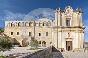 The Convent of Saint Agostino sitting on a steep cliff overlooking a deep canyon ravine filled with prehistoric sassi caves in photo