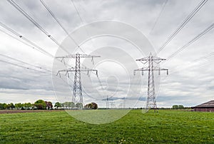 Converging high voltage cables and steel pylons in an agricultural landscape