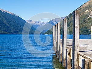 Converging mountain ridges beyond stunning blue water and jetty on Lake Roto-iti photo