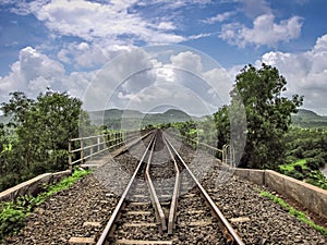 Converging rail track over bridge with nice blue sky and clouds background
