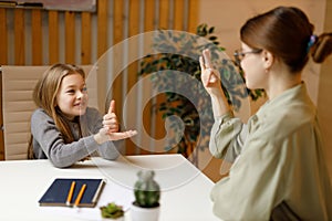 Conversation between teacher and student in sign language. Mute or deaf happy girl child at school