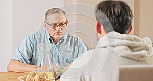 Conversation between two men of different ages at a table, having breakfast, lunch, older and