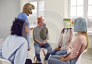 Conversation of young people in rubber masks on their heads during support group meeting.