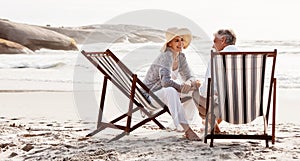 Conversations on the beach. Full length shot of an affectionate middle aged couple relaxing on loungers at the beach.