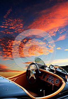 Convertible classic sports car parked in front of a dramatic sunset