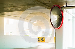 Convex safety mirror at curve of indoor car parking lot to reduce risk of accidents from blind corner or blind spots. Convex