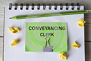 CONVEYANCING CLERK - words on a green sheet on a white notebook with a pencil and small pieces of paper