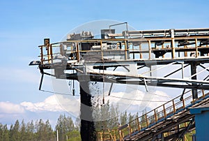 Conveyor belt carrying coal and emptying onto a huge pile.