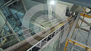 The conveyor belt of ingredients to the mixer. Workers in the workshop of the House-building plant. Industrial interior