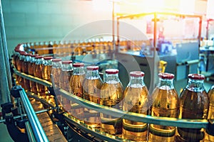 Conveyor belt, juice in bottles on beverage plant or factory interior in blue color, industrial production line