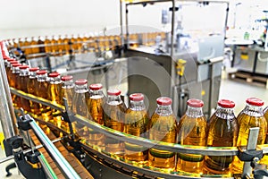 Conveyor belt or line in beverage factory or plant interior inside with modern industrial machine equipment. Bottles