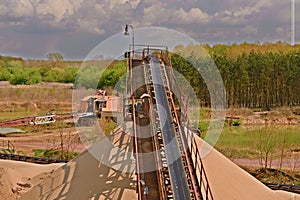 Conveyor belts and sand heaps. Construction industry. Sand quarry, heavy duty machinery. Horizontal photo.