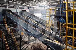 Conveyor with garbage at modern waste recycling plant transporting waste from receiving department to manual sorting department