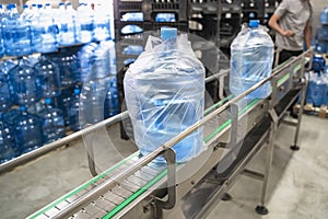 Conveyor line or belt with clean pure drinking water in plastic bottles packed in cellophane, loading finished goods at