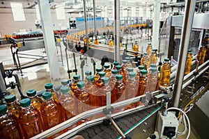 Conveyor line with plastic bottles of juice at modern factory equipment. Beverage manufacturing plant interior inside photo