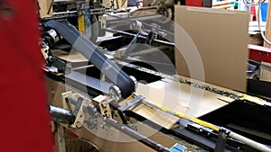 Conveyor line for the production of boxes. Machine carves cardboard boxes from sheets of cardboard. Enterprise for the production