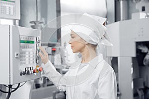 Conveyor switchboard concept. Factory engineer woman operating machine control panel in mill flour, milk food production