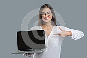 Convincing joyful woman pointing with finger at laptop