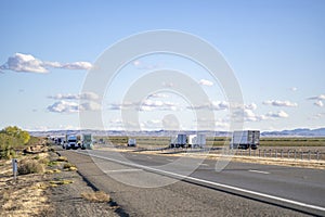 Convoy of the big rig semi trucks with semi trailers transporting cargo running in both directions photo