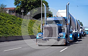 Convoy of big rigs semi trucks on the road with blue classic American bonnet semi tractor with bulk trailer photo