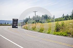 Convoy of big rigs semi trucks with semi trailert going on the turning road with hills