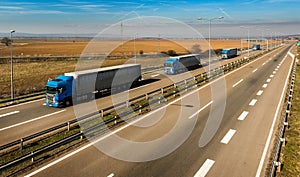 Convoy of Blue transportation trucks in line on a countryside highway