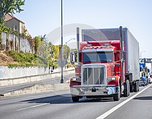 Convoy of classic big rigs semi trucks with semi trailers transporting cargo running in the line on the highway road