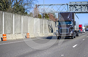 Convoy of different big rigs semi trucks with semi trailers transporting commercial cargo running on the wide multiline highway