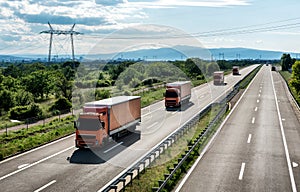 Convoy of Orange transportation trucks in line on a highway