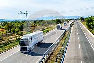 Convoy of transportation Lorry trucks in line passing on a country highway