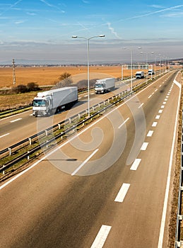 Convoy of white trucks in line on a rural countryside highway