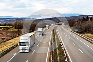 Convoy of White Trucks Or Traction Units In Motion On Highway