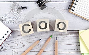 COO - Chief Operating Officer text on wooden block with office tools on the wooden background