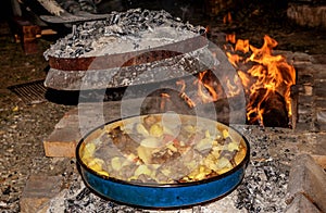 Coocking meet with patatoes and vegetables on a wood fire at ope