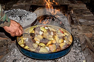 Coocking meet with patatoes and vegetables on a wood fire at ope