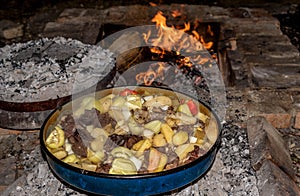 Coocking meet with patatoes and vegetables on a wood fire at ope