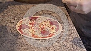 Cook adding ingredients on pizza base with tomato sauce and cheese