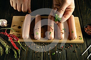 The cook adds aromatic parsley to the meat sausages before cooking. Concept of preparing a delicious breakfast