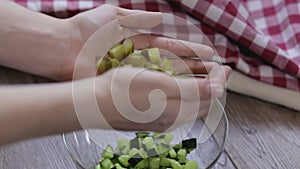 Cook adds cucumber to a salad close-up