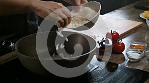 The cook adds the raw onion to the pan to caramelize it.