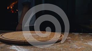 Cook in apron taking hot and hot pizza out of oven