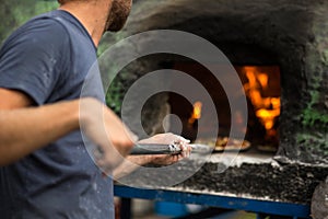 Cook baking pizza in a traditional stone oven