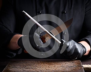 Cook in black latex gloves sharpens a knife