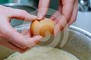 Cook breaking an egg into the bowl in a bakery