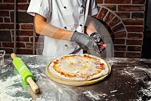 Cook Chef making delicious pizza at the restaurant, close-up