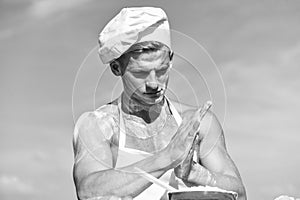 Cook or chef with muscular shoulders and chest covered with flour. Chef cook preparing dough for baking with flour