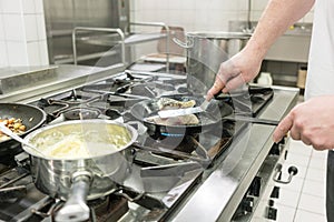 Cook or chef in Restaurant frying carp fish in pan on stove