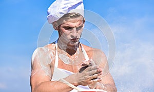 Cook or chef with muscular shoulders and chest covered with flour. Baker concept. Chef cook preparing dough for