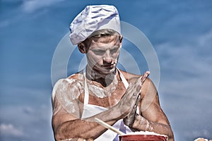 Cook or chef with sexy muscular shoulders and chest covered with flour. Chef cook preparing dough for baking with flour